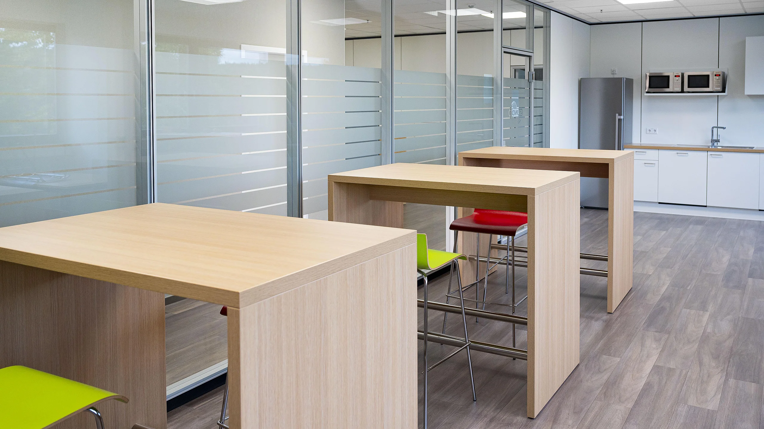 Aufenthaltsräume mit individuell gefertigten Hochtischen, farbigen Stühlen und Kücheneinbauten